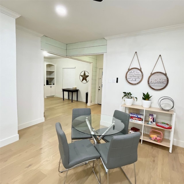 dining area featuring baseboards, light wood finished floors, and ornamental molding