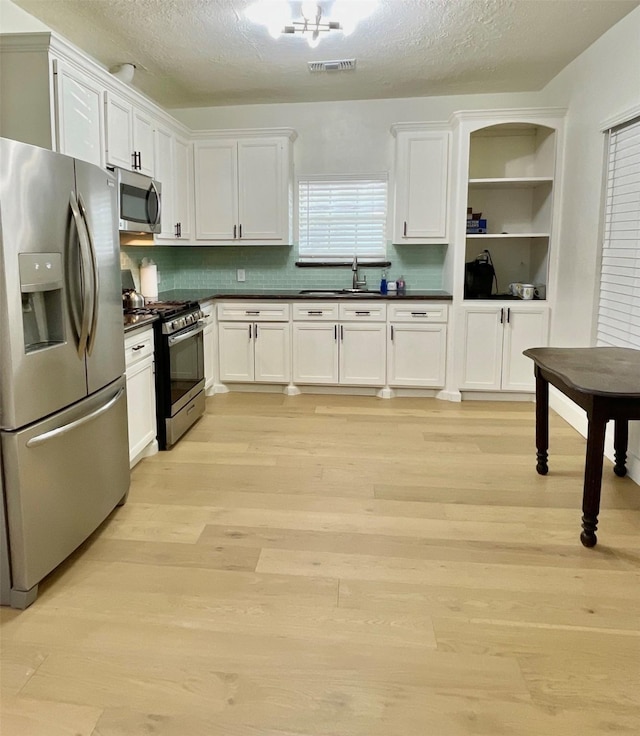 kitchen with dark countertops, visible vents, appliances with stainless steel finishes, and white cabinetry