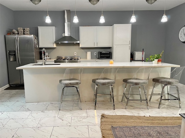 kitchen featuring wall chimney range hood, gas range oven, stainless steel fridge, marble finish floor, and a sink