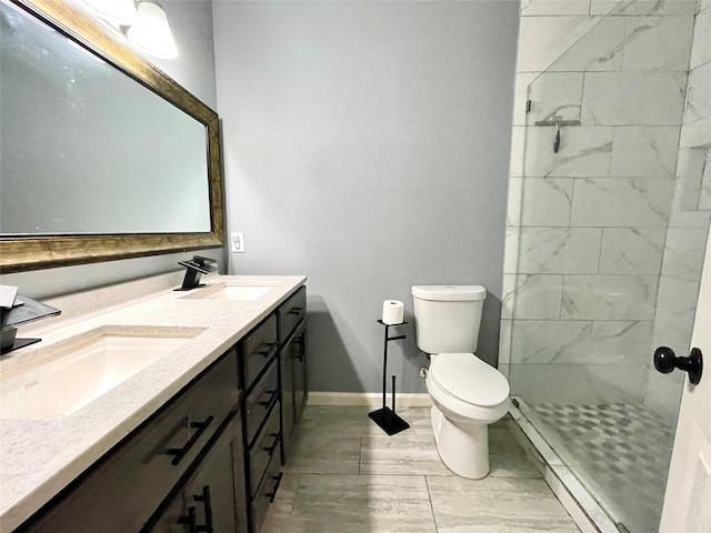 full bath featuring double vanity, toilet, a tile shower, and a sink