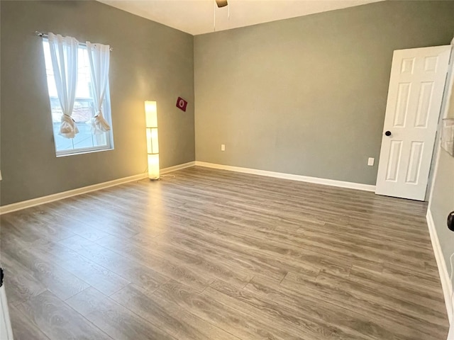 unfurnished room with a ceiling fan, baseboards, and wood finished floors