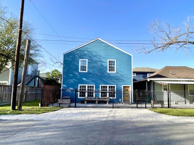 rear view of property with a fenced front yard and a gate