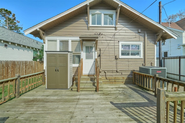 back of property featuring an outbuilding, central AC, fence, a storage shed, and a wooden deck