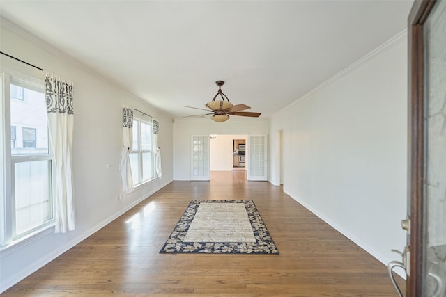 entryway with baseboards, wood finished floors, a ceiling fan, and crown molding