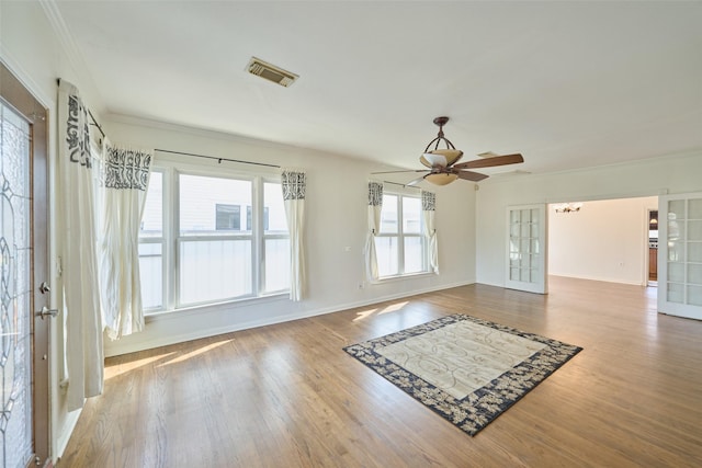 interior space with visible vents, crown molding, baseboards, ceiling fan, and wood finished floors