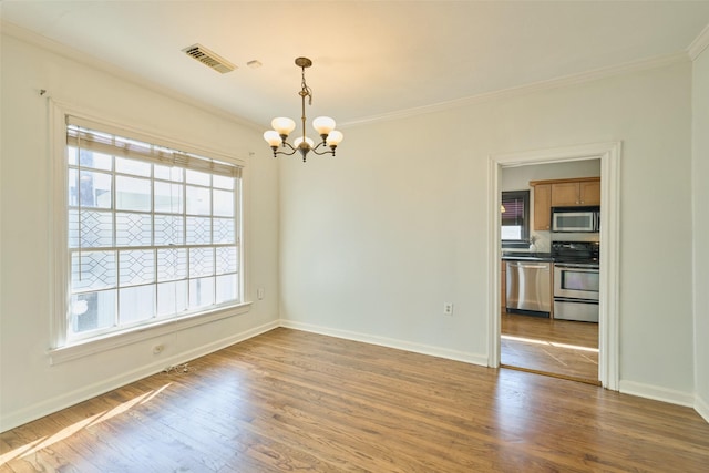 spare room featuring ornamental molding, wood finished floors, visible vents, and a chandelier