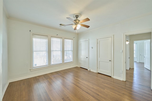 unfurnished bedroom featuring dark wood-style floors, baseboards, multiple closets, and ornamental molding