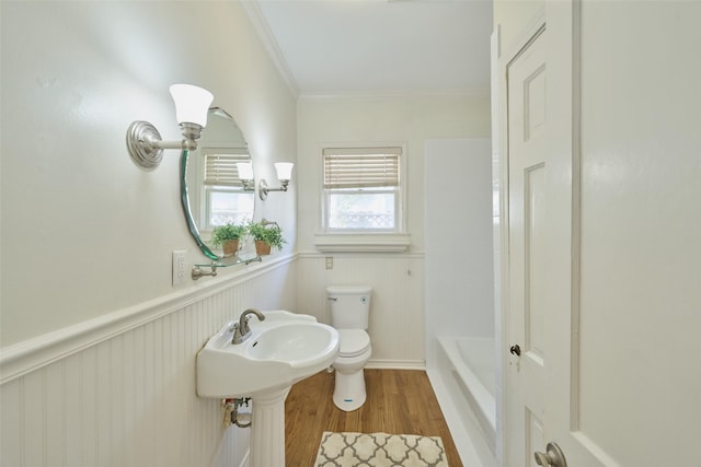 bathroom featuring toilet, ornamental molding, wainscoting, wood finished floors, and a sink