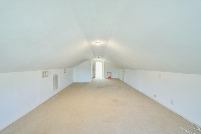 additional living space with visible vents, light carpet, and lofted ceiling