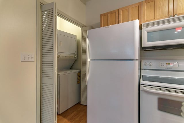 kitchen featuring stacked washer and clothes dryer, white appliances, and light wood-type flooring