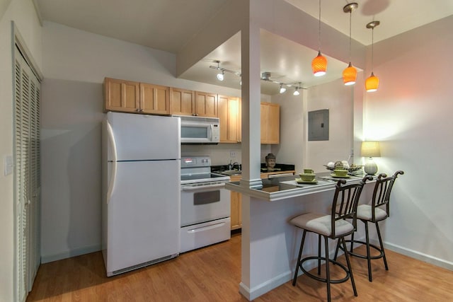 kitchen featuring white appliances, a breakfast bar, a peninsula, electric panel, and light wood-type flooring