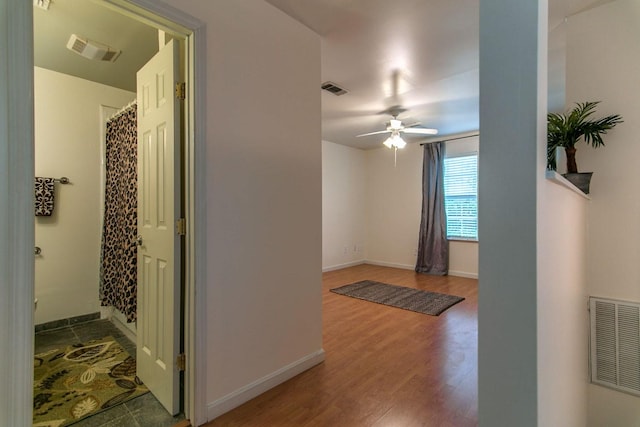 hallway featuring visible vents, baseboards, and wood finished floors