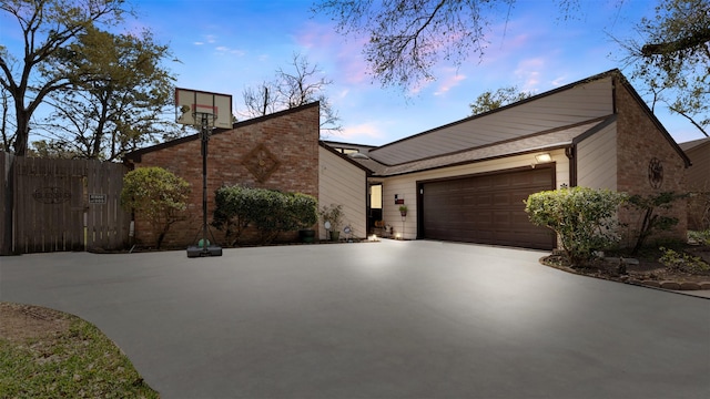 view of front of house featuring brick siding, concrete driveway, a garage, and fence