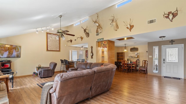 living room featuring light wood-style flooring, a ceiling fan, visible vents, and a healthy amount of sunlight