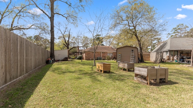 view of yard featuring an outbuilding, a shed, a fenced backyard, and a vegetable garden