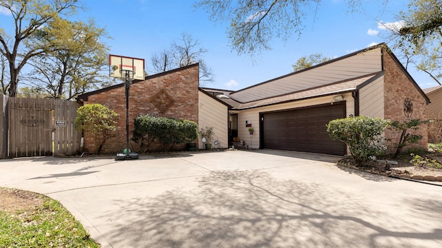 view of front facade featuring concrete driveway, an attached garage, fence, and brick siding