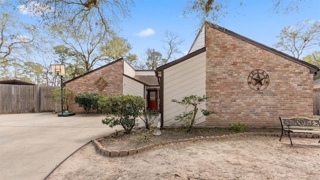 view of property exterior featuring brick siding and fence