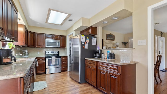 kitchen with visible vents, backsplash, appliances with stainless steel finishes, light wood-style floors, and a sink