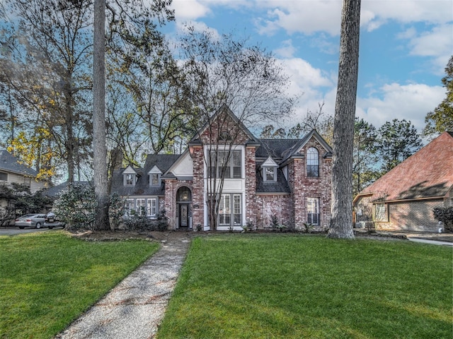 tudor-style house with brick siding and a front lawn