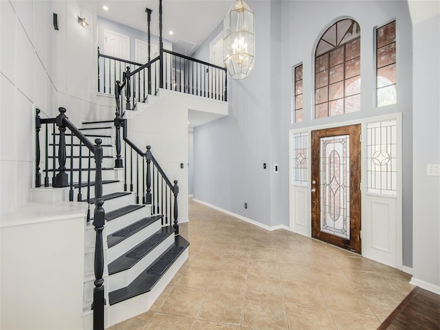 tiled foyer entrance featuring stairway, baseboards, recessed lighting, a towering ceiling, and a chandelier