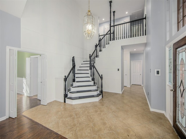 entryway featuring a notable chandelier, wood finished floors, stairway, baseboards, and a towering ceiling