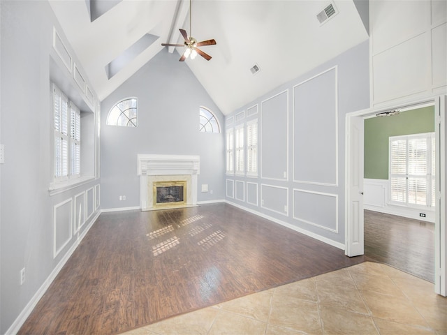 unfurnished living room featuring visible vents, a fireplace, tile patterned floors, a decorative wall, and a ceiling fan