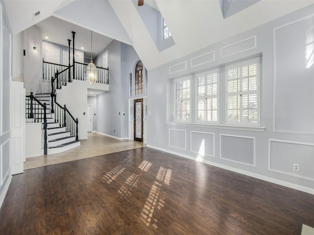 foyer with stairs, a decorative wall, wood finished floors, and visible vents