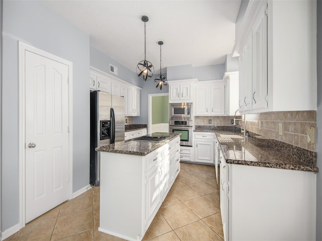 kitchen with a sink, a kitchen island, white cabinetry, appliances with stainless steel finishes, and light tile patterned flooring