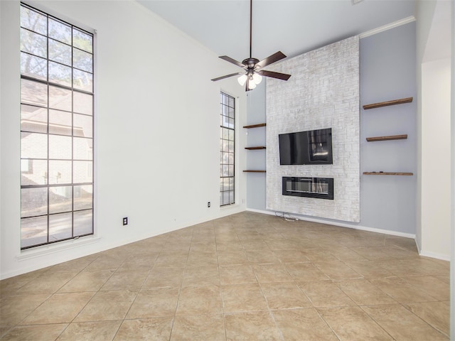 unfurnished living room with built in features, a large fireplace, light tile patterned floors, baseboards, and ceiling fan