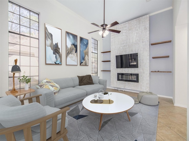 living area with built in features, a ceiling fan, baseboards, light tile patterned floors, and a large fireplace