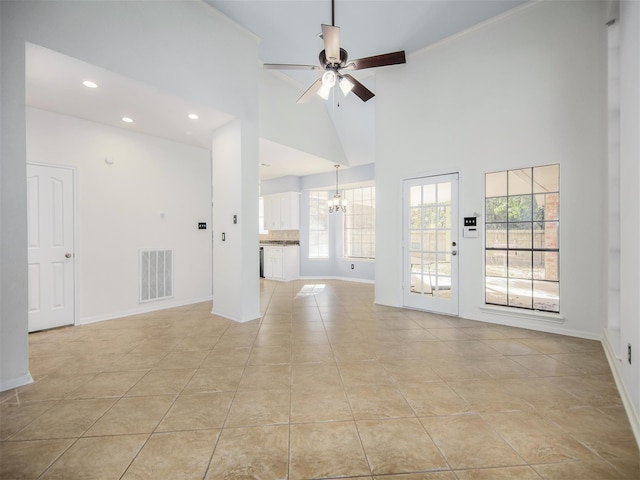 unfurnished living room featuring visible vents, ceiling fan with notable chandelier, a high ceiling, light tile patterned floors, and baseboards