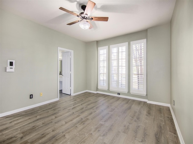 empty room featuring baseboards, wood finished floors, and ceiling fan