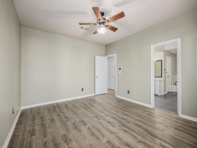 unfurnished bedroom with wood finished floors, visible vents, ensuite bathroom, and baseboards