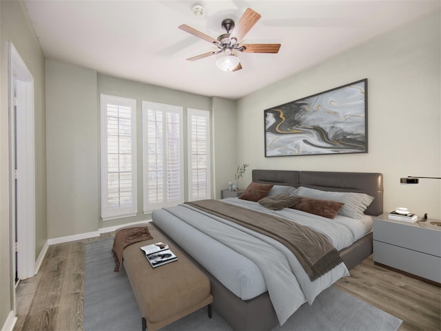 bedroom with a ceiling fan, wood finished floors, and baseboards