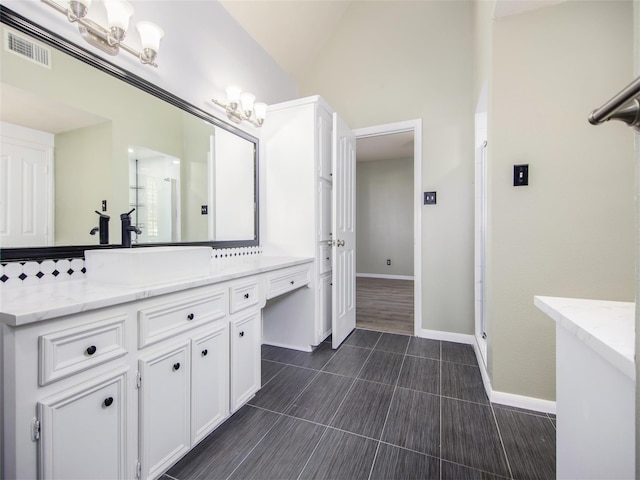 bathroom featuring visible vents, baseboards, vaulted ceiling, a stall shower, and vanity