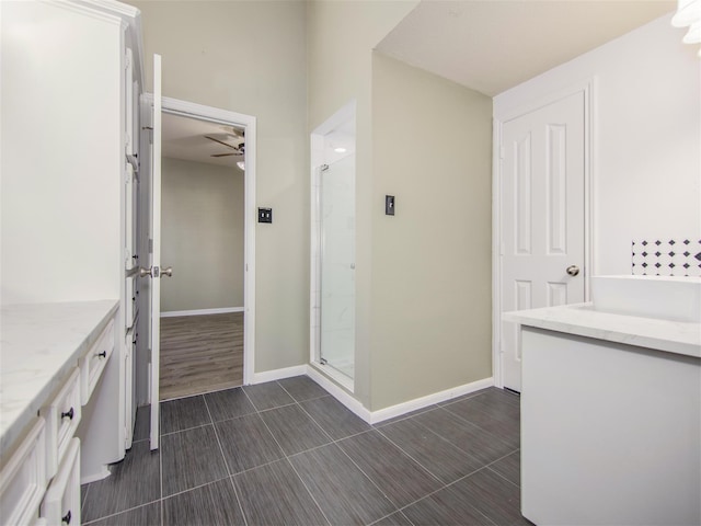 bathroom with vanity, a ceiling fan, a stall shower, and baseboards