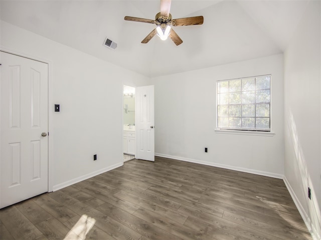 unfurnished bedroom featuring visible vents, ensuite bath, dark wood-style floors, baseboards, and lofted ceiling