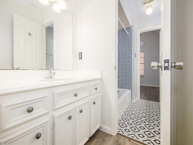 bathroom featuring visible vents, baseboards, shower / tub combination, wood finished floors, and vanity