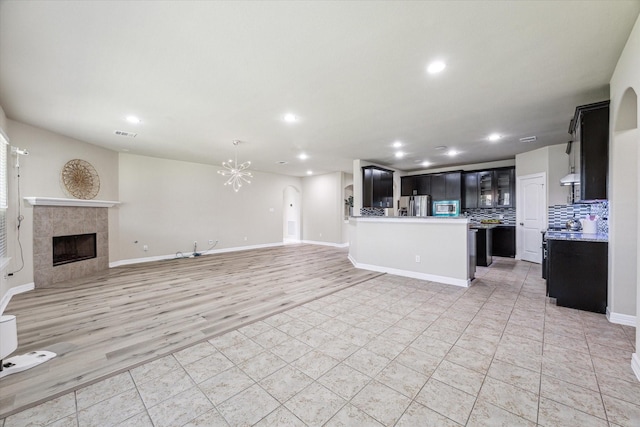 unfurnished living room with visible vents, baseboards, a fireplace, recessed lighting, and a notable chandelier