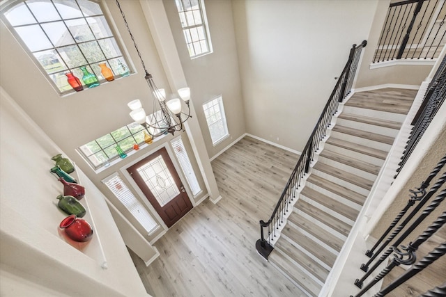 entryway featuring visible vents, wood finished floors, a high ceiling, an inviting chandelier, and stairs