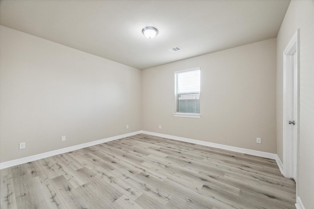 empty room featuring visible vents, light wood-style floors, and baseboards