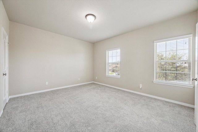 carpeted spare room featuring baseboards