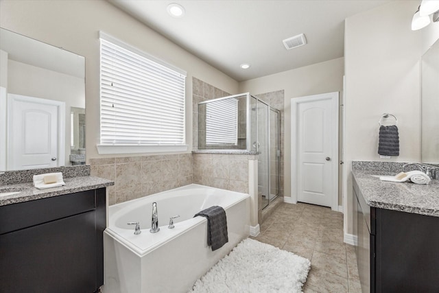 full bath featuring a shower stall, two vanities, and visible vents