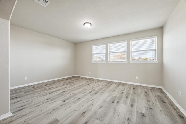 empty room with visible vents, baseboards, and light wood finished floors