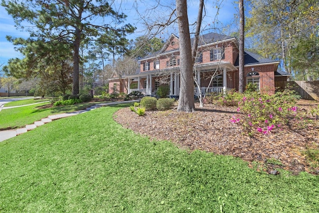 view of front of house featuring a front lawn, a porch, and brick siding