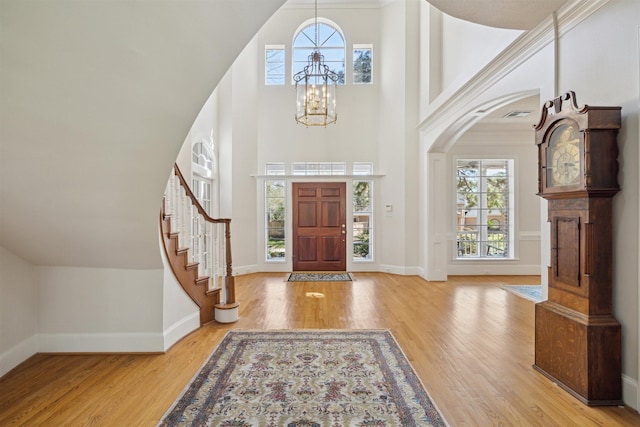 entrance foyer with stairway, baseboards, an inviting chandelier, and wood finished floors