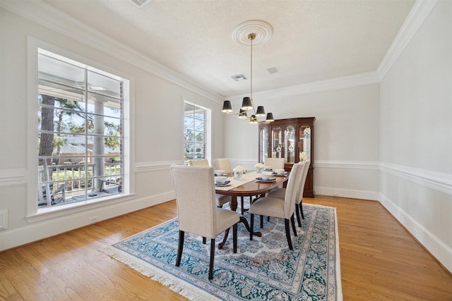 dining space with light wood-style flooring, visible vents, a chandelier, and ornamental molding