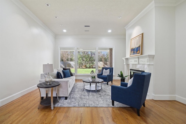 living area featuring crown molding, a fireplace, light wood-style floors, and baseboards