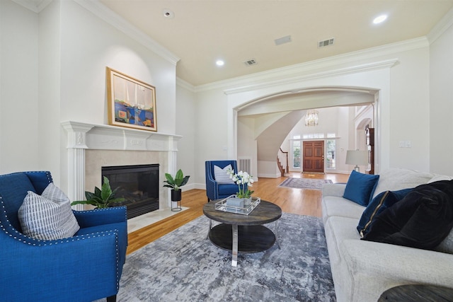 living room featuring wood finished floors, crown molding, visible vents, and arched walkways