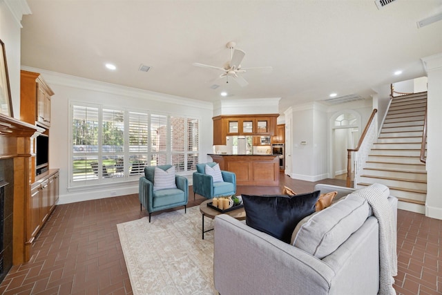 living room with crown molding, ceiling fan, stairs, recessed lighting, and brick floor